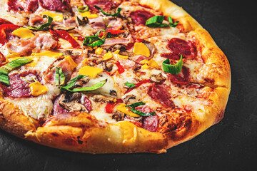 Pizza with Mozzarella cheese, salami, chicken meat, beef, ham, Tomato sauce, pepper, spices. Italian pizza on Dark grey black slate background