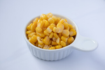 Corn boiled in a white ceramic cup on a white background.