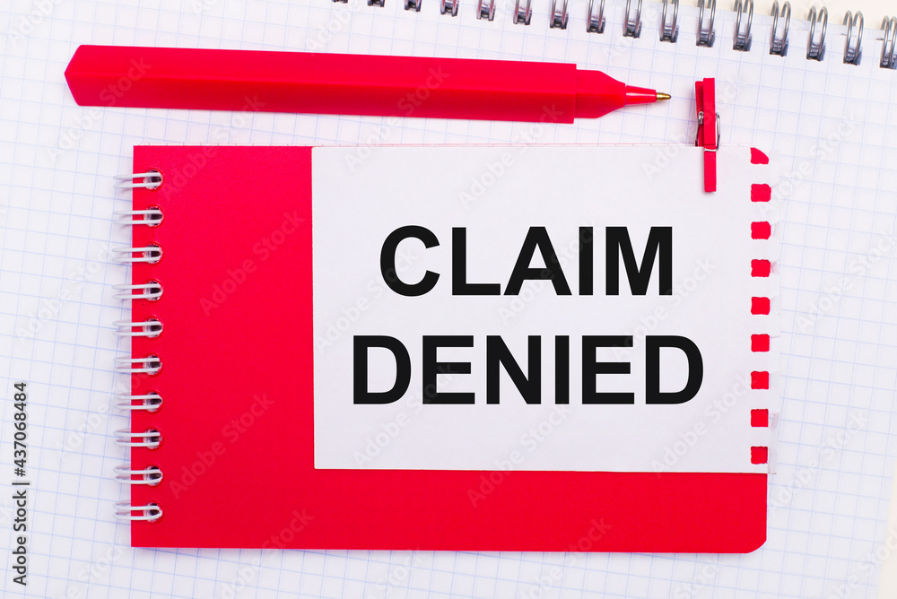 Poster on a white notepad, a red pen, a red notepad and a white sheet of paper with the text claim denied