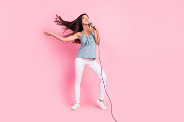 Fototapeta na wymiar Full length photo of cheerful nice young woman sing stage good mood fly hair isolated on pink color background