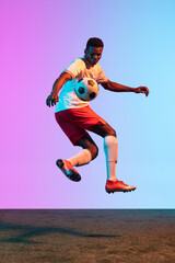 Fototapeta na wymiar One African man, professional soccer football player training isolated on gradient blue pink background in neon light.