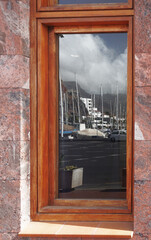 The reflection on a shop window, where we see the harbor, the mountains, the sky, the boats, in the port of  San Sebastian, Canary Islands