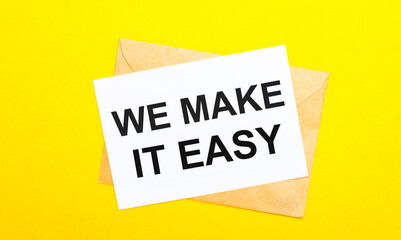 On a yellow background, an envelope and a card with the text WE MAKE IT EASY. View from above