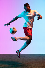 Portrait of African professional football player standing isolated on gradient blue pink background in neon light. Back view © master1305