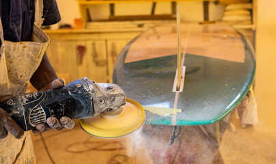 An African Craftsman surfboard Shaper working in a repair workshop