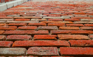 Wall of old red brick with weathered cement. At an angle