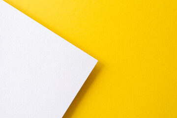 Yellow and white colored paper with shadows as background, top view, space for text, flat lay