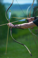 professional archer shooting with modern longbow at forest 