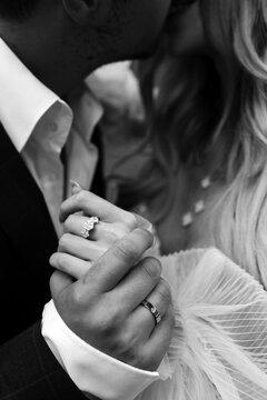 Hands of the bride and groom. Wedding rings on the fingers of the newlyweds. Young hugs. Black and white photo.