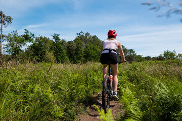 pretty young athletic woman mountain biking in nature