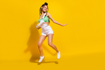 Full size photo of afro american charming happy young woman jump up good mood dance isolated on yellow color background