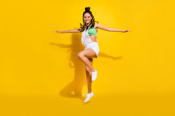 Fototapeta na wymiar Full body photo of afro american young funky happy woman jump up hands wings isolated on yellow color background