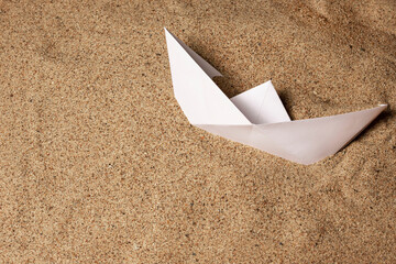 White paper boat lies on the sea sand