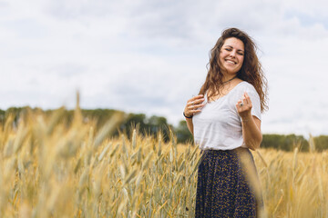 Young happy woman in rustic dress walking In A grassy Field in summer meadow. Space for text. Atmospheric authentic moment. Rural slow life. Sensitivity to nature concept