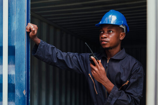 black african amarican man worker working control loading freight containers at commercial shipping dock. cargo freight dock and import export logistic concept.