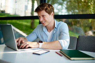 Cheerful male programmer updating software settings on netbook technology using 4g internet...