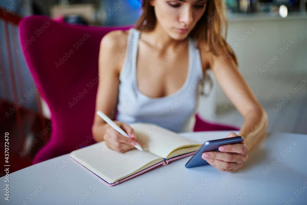 Poster blurred female student using cellphone device for browsing website while learning at table desktop, 