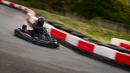 A panning shot of a racing kart as it circuits a track.