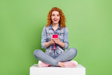Full size photo of young excited girl happy positive smile blogger like repost use smartphone isolated over green color background