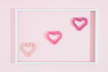 Minimal, modern love concept. Three hearts in white frame. On brite pink background.