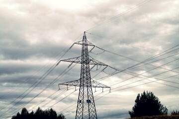 Torres de alta tensión para conducir la electricidad. Fotografía tomada un día nublado donde destaca la silueta con el cielo oscuro.