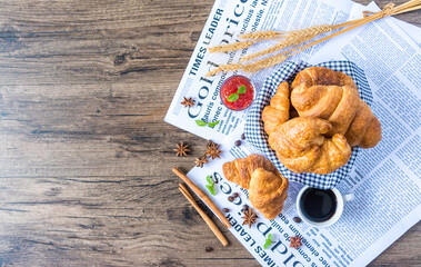 Close Up of Fresh Baked Croissant on wood table with Coffee Mug and  news paper on Relaxing Morning at Home, Bread and coffee, breakfast Healthy food of the city life