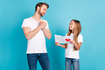 Portrait of cute girl giving paper card satisfied dad look each other have good mood isolated on blue color background