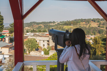 Girl watching from the viewpoint of the old mining tower, with a tourist telescope to observe the...