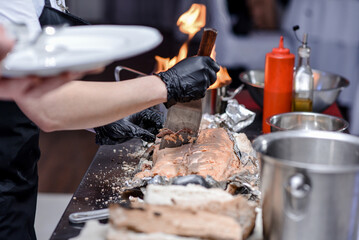 Baked fish in foil and salt on the fire, cutting fish, delicious food.
