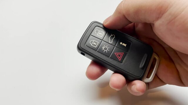 hand pushing car key remote on white background