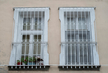 Old two wooden windows with decorative metal grille and flowers