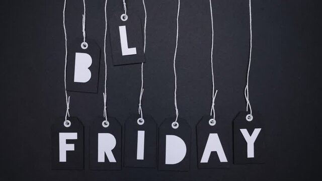 Stop Motion Animation. Paper cut out tags with letters spelling Black Friday fall into frame from top