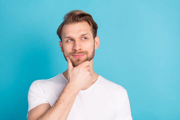 Photo of young satisfied person arm on chin look interested empty space isolated on blue color background