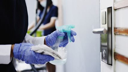 Housekeeper wear gloves to clean door handles. with antiseptic during viral or COVID-19 epidemic....
