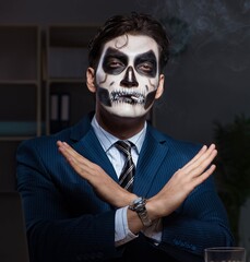 Businessman with scary face mask working late in office