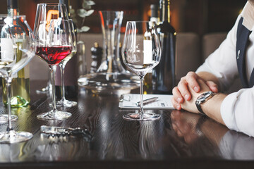 A wine waiter with a tablet near the glasses in the restaurant is waiting for the tasting to begin