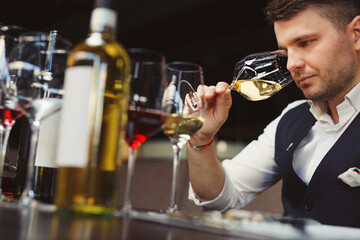 Sommelier smells white wine poured into glass at table
