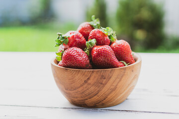 Strawberries in wooden bowl on green background