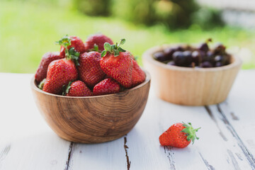 Strawberries in wooden bowl on green background