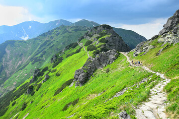 Fototapeta na wymiar The ridgeway which leads from mount Kasprowy wierch along the polish-slovakian border. Some hikers on the track. High Tatras, Poland.