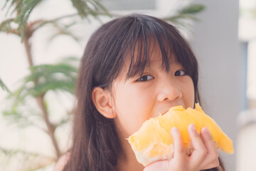 7 years old asian kid girl eat fresh fruit.Little asian thai girl eating durian fruit at home...