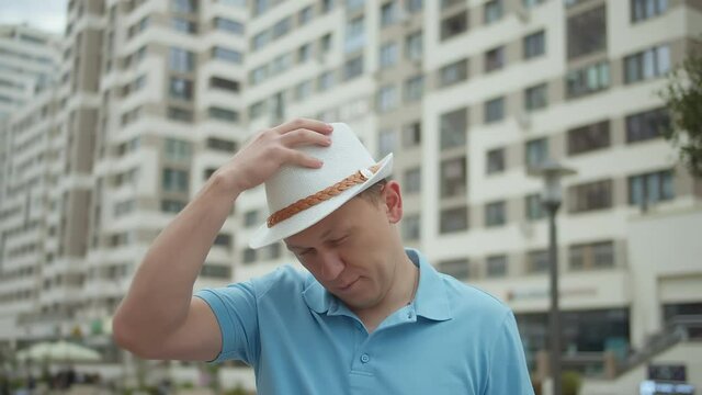 Portrait of attractive man in hat on background of city buildings, camera tracking