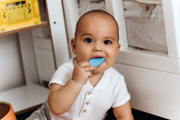 Sweet little baby playing on the floor in his room. Funny baby with blue wooden block in his mouth