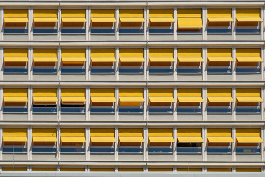 pattern of orange shutter sun protection at a facade of a modern concrete building