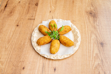 Croquettes stuffed with béchamel and chicken garnished with sprouts on recycled cardboard plate