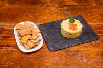 Peruvian causa lime&ntilde;a on black slate plate accompanied by rega&ntilde;&aacute;s to spread