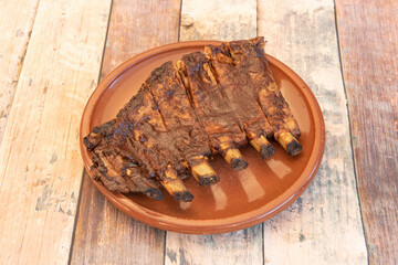 Semi-chopped pork ribs marinated with barbecue sauce on an earthenware plate