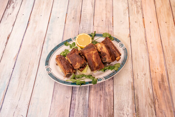 Chinese style fried pork ribs on nice plate with coriander and lemon
