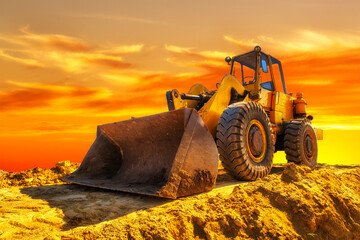 A stopping yellow excavator at an incredibly beautiful sunset