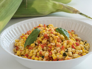 Corn and red pepper side dish in white serving bowl